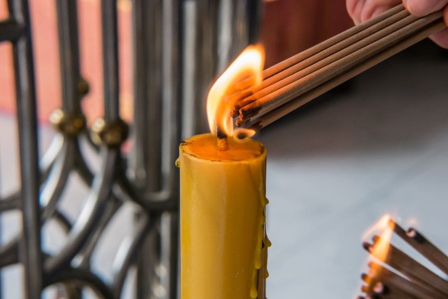 Lighting incense on yellow candle