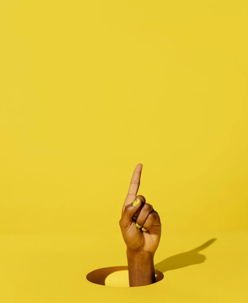 Index finger raised with a yellow background