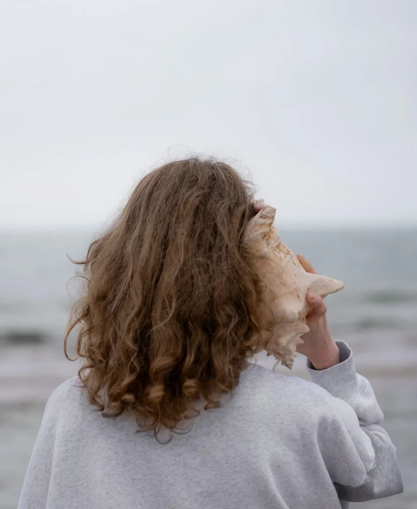 a woman listening to something inside the sea shell