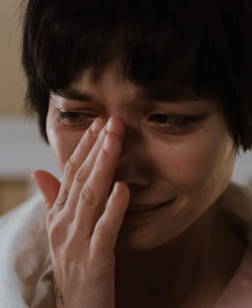woman crying while rubbing her eyes