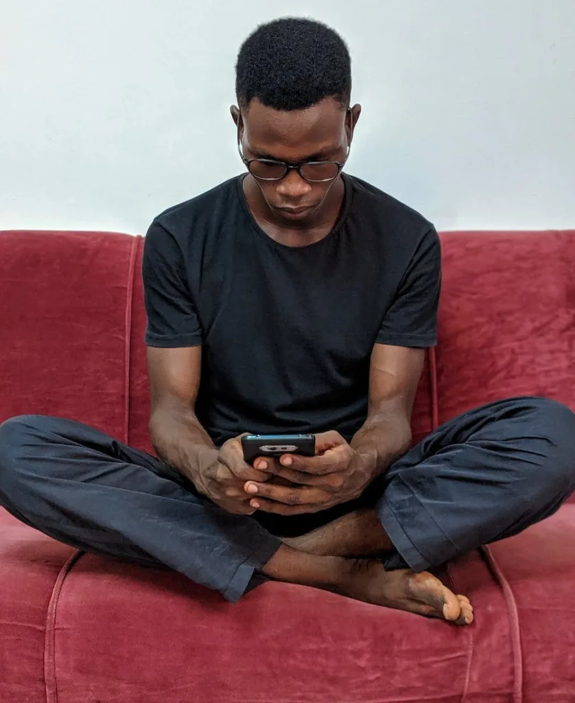 Man using a mibile phone sitting on the couch 